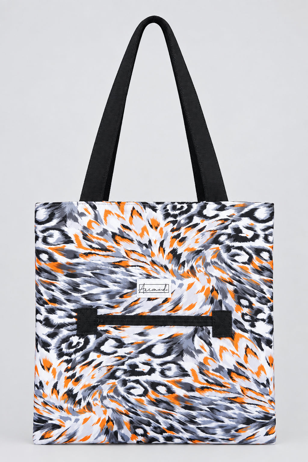 A tote bag with a black and white abstract swirl pattern and bright orange accents, featuring black shoulder straps and a black horizontal zipper pocket on the front.