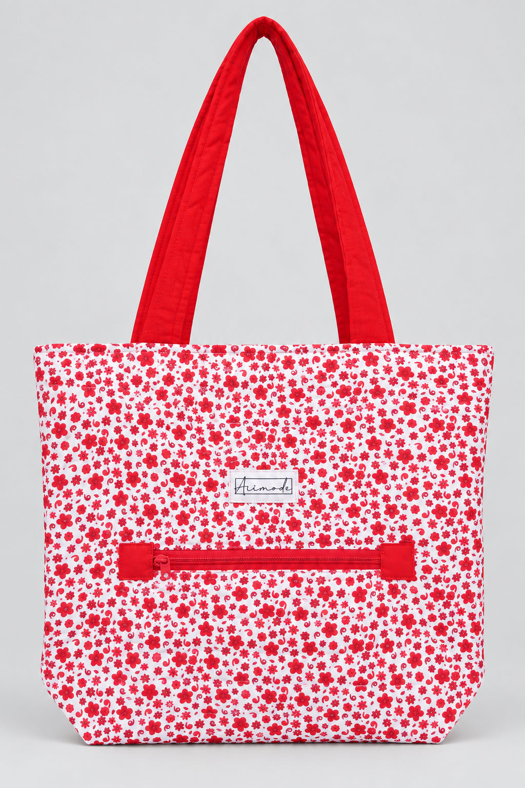 A tote bag with a red and white floral pattern, featuring solid red shoulder straps and a matching red zipper pocket on the front.