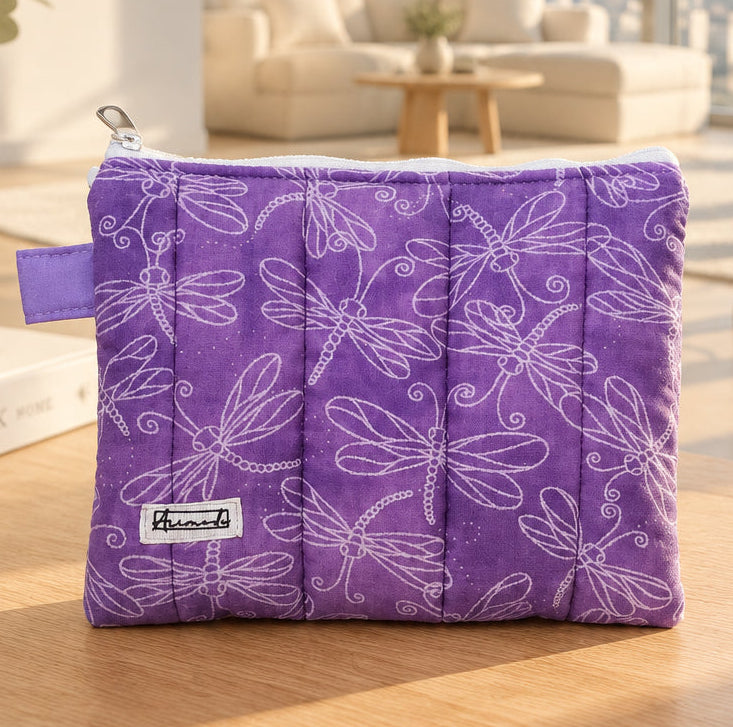 A purple quilted fabric pouch with a white dragonfly pattern.